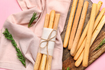 Wooden board with tasty Italian Grissini on pink background