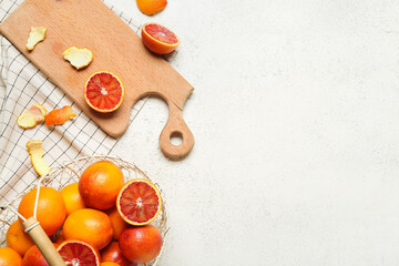Wooden board and basket with tasty blood orange fruits on white background