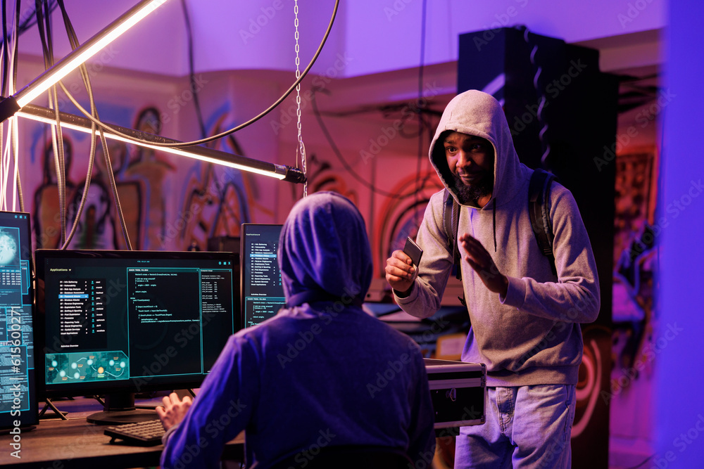 Poster african american hacker holding ssd with illegal malware for password cracking. criminal in hood bri