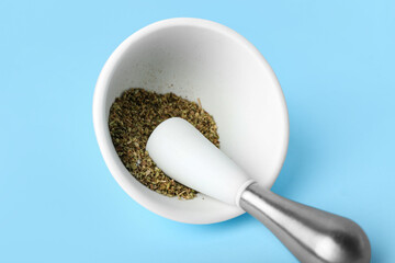 Mortar and pestle with spices on blue background, closeup