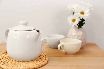 Tea set with wicker mat and flowers  on wooden table