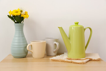 Teapot with cups and flowers on wooden table