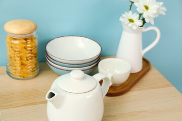 Composition with beautiful tea set, flowers and different kitchen stuff on wooden table
