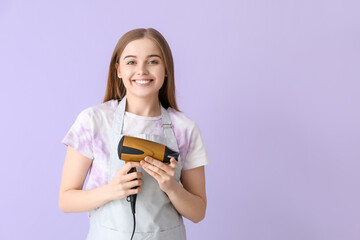 Female hairdresser with dryer on lilac background