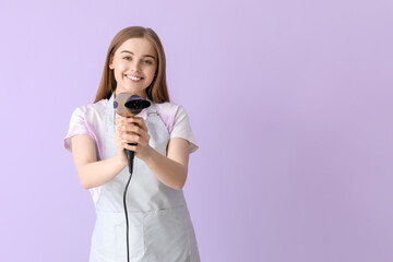 Female hairdresser with dryer on lilac background