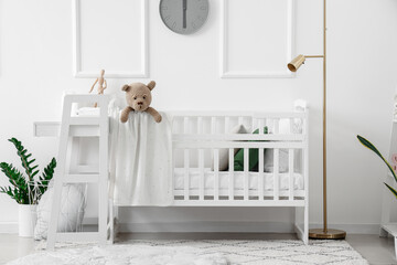 Interior of light bedroom with baby crib and changing table