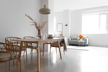Interior of stylish dining room with blooming sakura branches on table