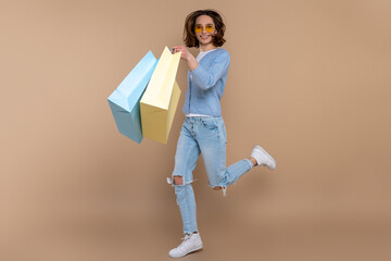 Happy joyful woman in casual clothing running jumping with shopping bags