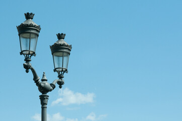 Fototapeta na wymiar Front view, medium distance of, two historic, handmade, metal, street lamps, against blue sky, in Reim, France