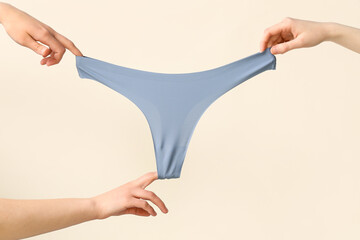 Female hands with stylish panties on light background, closeup