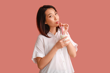 Beautiful Asian woman with bottle of milk on pink background