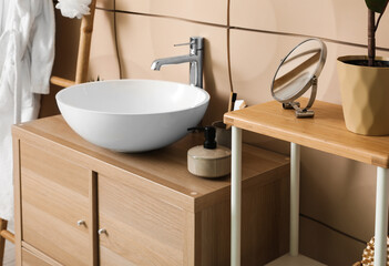 Fototapeta na wymiar Sink bowl and bath accessories on wooden cabinet in bathroom