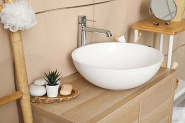 Sink bowl with bath accessories on table in bathroom