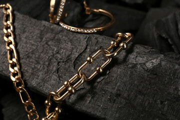Fototapeta na wymiar Beautiful chain bracelets and earrings on black charcoal, closeup