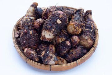 Organic taro fruit in bamboo weave plate on white background.