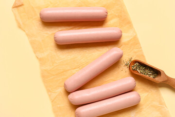 Baking paper with tasty thin sausages on beige background