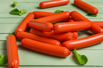 Tasty thin sausages and spinach on green wooden background