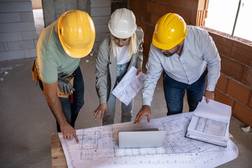 A female architect and a focused construction managers engage in an animated discussion, analyzing...