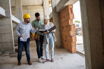 A female architect and construction manager work together on-site, discussing blueprints and coordinating to bring their project to life.