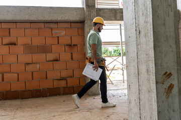 
The construction manager confidently walks through the construction site, observing progress,...