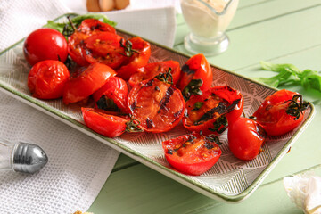 Plate with tasty grilled tomatoes and arugula on green wooden background