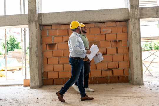 The architect and construction manager walk together through the bustling construction site, inspecting progress, discussing plans, and ensuring seamless coordination for successful project completion