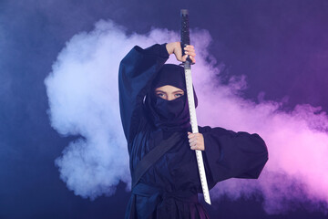 Female ninja with sword on dark background © Pixel-Shot