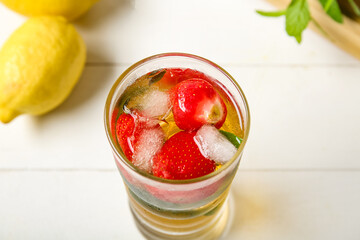 Glass of ice tea with strawberry and mint on white background