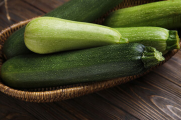 Wicker bowl with fresh green zucchini on wooden background
