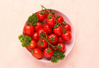 Bowl with fresh cherry tomatoes and parsley on pink background