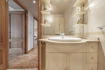 Small bathroom with a white porcelain sink embedded in a marble countertop, a small white wooden