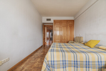 Naklejka premium Bedroom with two double beds, plaid bedspread, and built-in oak