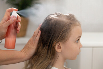 Women's hands apply a remedy for lice and nits on the head of a little girl. Getting rid of parasites and pests, childhood diseases. - obrazy, fototapety, plakaty