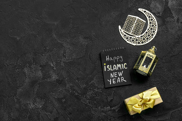 Notebook with text HAPPY ISLAMIC NEW YEAR, fanous, crescent and gift box on dark background