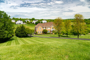 Fototapeta na wymiar Large, beautiful, single-family brick country house. Large lawn and green trees.