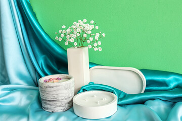Gypsophila flowers, blanket and candles on table near green wall in room, closeup
