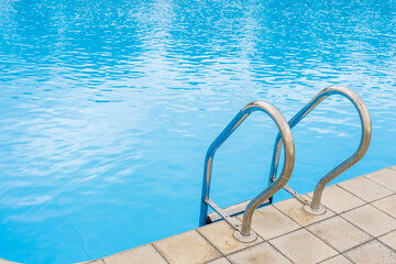 Fototapeta premium Swimming pool with selective focus on metal stairs and copy space for text.