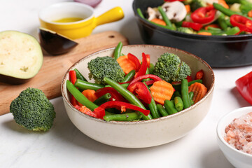 Bowl with fresh vegetables on light background