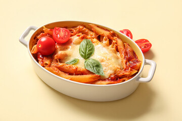 Baking dish of pasta with tomato sauce and cheese on beige background