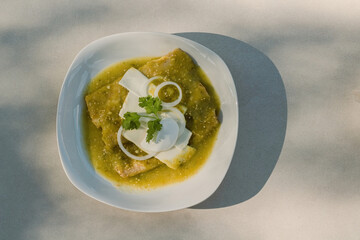 The Mexican enchiladas verdes, a staple food in Mexican cuisine, are served on a plate