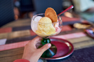 Close up of a delicious looking ice cream cup. Close Up View of Scoops of Strawberry Lemon Vanilla Ice Cream and Sweet Biscuit in restaurant.Served in Glass Dish on Rustic Wooden Table            