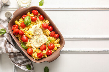 Baking dish of tasty pasta with tomatoes and feta cheese on white wooden background
