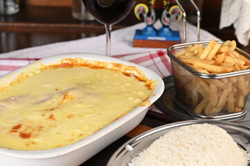 bolognese lasagna baked with cheese ham red sauce spices and meat with french fries and rice.