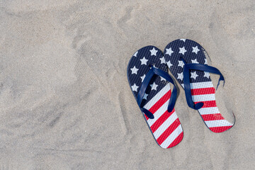vacation concept with patriotic red white and blue flip flops on the beach