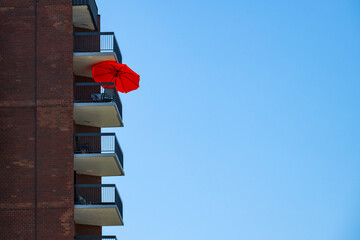 A red parasol on a tall building balcony