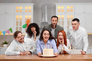 Happy friends with tasty cake celebrating birthday in kitchen