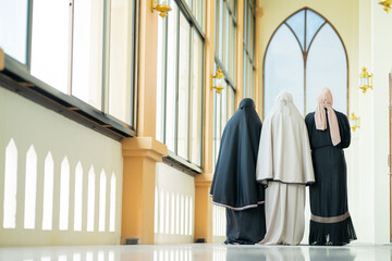 Naklejka premium Many groups of Asian Muslim women in the Islamic religion in hijabs of cream and black color. She was praying in a beautiful mosque out of respect for God.