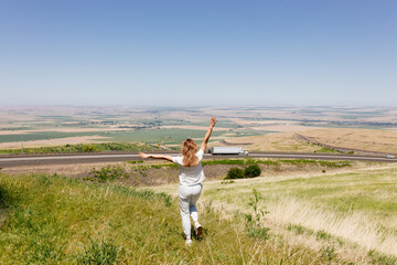 Fototapeta premium Beautiful summer landscape with meadows and a road from a bird's eye view. Nature in Oregon. A girl in sportswear with red hair walks in a summer meadow, rests in nature, admires nature