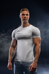 Young athletic sexy man in white t-shirt on black background