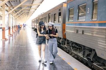 Two young woman traveler tourist  booking train queue by smartphone . Active and travel lifestyle concept